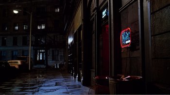 Movie still from “Altered States” (1980), directed by Ken Russell – A dark alley with a television on the side of the building; Wide shot, High angle