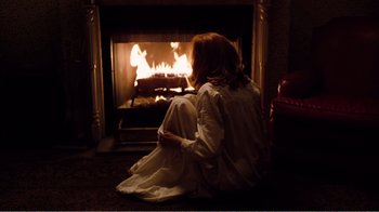 Movie still from “Altered States” (1980), directed by Ken Russell – A woman sitting in front of a fire place; Wide shot, High angle