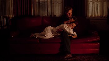 Movie still from “Altered States” (1980), directed by Ken Russell – A man and a woman sitting on a red couch; Medium shot, High angle