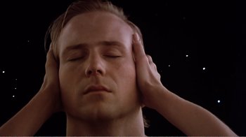 Movie still from “Altered States” (1980), directed by Ken Russell – A man with his eyes closed and a hand touching his head; Close Up shot, Low angle