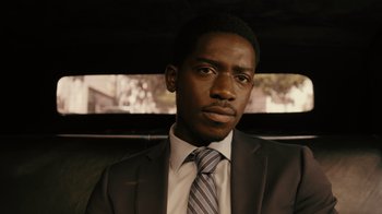 Movie still from “Snowfall” (2017), directed by Hiro Murai – A man wearing a suit and tie sitting in a car; Close Up shot, Low angle