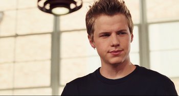 Movie still from “Alvin and the Chipmunks: The Squeakquel” (2009), directed by Betty Thomas – A young man with blonde spiky hair wearing a black t - shirt; Close Up shot, Over the shoulder angle