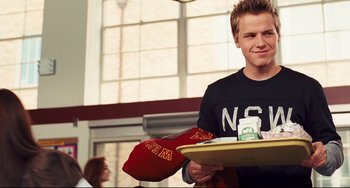 Movie still from “Alvin and the Chipmunks: The Squeakquel” (2009), directed by Betty Thomas – A young man holding a tray of food and a hat; Medium shot, Over the shoulder angle