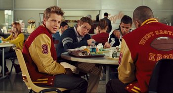 Movie still from “Alvin and the Chipmunks: The Squeakquel” (2009), directed by Betty Thomas – A group of young men sitting at a table eating food; Medium shot, Over the shoulder angle