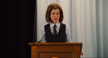 Movie still from “Alvin and the Chipmunks: The Squeakquel” (2009), directed by Betty Thomas – A woman is speaking at a podium in front of a curtain; Medium shot, Low angle
