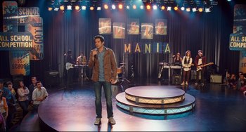 Movie still from “Alvin and the Chipmunks: The Squeakquel” (2009), directed by Betty Thomas – A man standing on a stage singing into a microphone; Wide shot, High angle