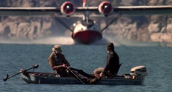 Movie still from “Always” (1989), directed by Steven Spielberg – Two people in a boat in front of an airplane; Wide shot, Low angle