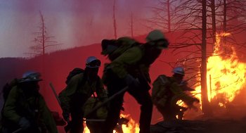 Movie still from “Always” (1989), directed by Steven Spielberg – A group of people that are standing in front of a fire; Wide shot, Low angle