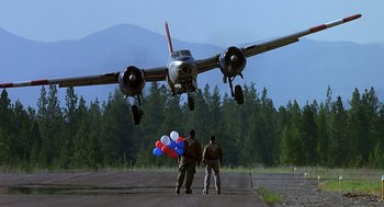 Movie still from “Always” (1989), directed by Steven Spielberg – Two men standing under a large propeller plane; Wide shot, Low angle