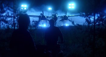 Movie still from “Always” (1989), directed by Steven Spielberg – Two people standing in front of an airplane at night; Wide shot, Low angle
