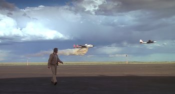 Movie still from “Always” (1989), directed by Steven Spielberg – A man walking across a runway near a jet plane; Extreme Wide shot, Low angle
