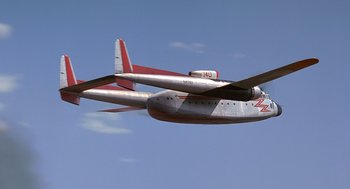 Movie still from “Always” (1989), directed by Steven Spielberg – An airplane is flying in the sky on a sunny day; Extreme Wide shot, Low angle
