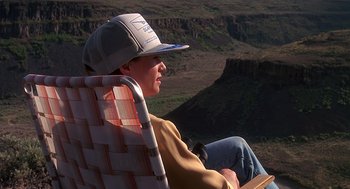 Movie still from “Always” (1989), directed by Steven Spielberg – A man sitting on a lawn chair in the desert; Wide shot, High angle