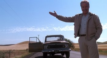 Movie still from “Always” (1989), directed by Steven Spielberg – A man standing on the side of a road near a truck; Wide shot, Low angle