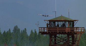 Movie still from “Always” (1989), directed by Steven Spielberg – An airplane is flying in the sky over a tree covered forest; Extreme Wide shot, Low angle