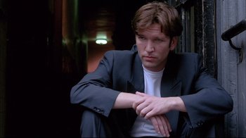 A man in a suit sitting on a chair looking sad