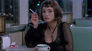 A woman sitting at a table with a cigarette in her mouth
