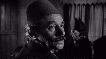 Movie still from “America America” (1963), directed by Elia Kazan – A man with a mustache and a hat on his head; Close Up shot, Over the shoulder angle