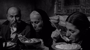 Movie still from “America America” (1963), directed by Elia Kazan – Two people sitting at a table eating food; Medium shot, High angle