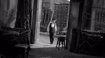 Movie still from “America America” (1963), directed by Elia Kazan – A black and white photo of a man standing in an open doorway; Wide shot, High angle
