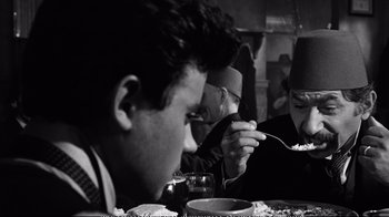 Movie still from “America America” (1963), directed by Elia Kazan – A group of people sitting at a table eating food; Close Up shot, Over the shoulder angle
