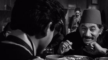 Movie still from “America America” (1963), directed by Elia Kazan – Two men sitting at a dinner table with a plate of food in front of them; Close Up shot, Over the shoulder angle