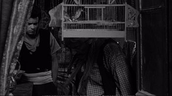 Movie still from “America America” (1963), directed by Elia Kazan – A person with a bird cage on their head; Medium shot, Over the shoulder angle