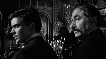 Movie still from “America America” (1963), directed by Elia Kazan – A man and a woman standing next to each other in front of candles in a room; Medium shot, Over the shoulder angle