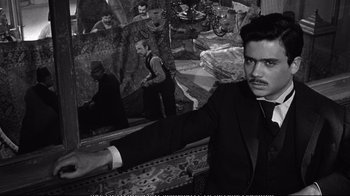 Movie still from “America America” (1963), directed by Elia Kazan – A black and white photo of a man in a suit and tie in front of a mirror; Medium shot, Over the shoulder angle