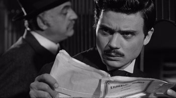Movie still from “America America” (1963), directed by Elia Kazan – A man in a suit and tie looking at a paper bag; Close Up shot, Over the shoulder angle