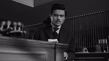 Movie still from “America America” (1963), directed by Elia Kazan – A black and white photo of a man in a suit and tie; Medium shot, Low angle