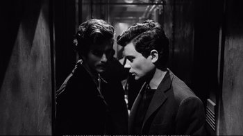 Movie still from “America America” (1963), directed by Elia Kazan – Two young men standing next to each other in front of a building; Close Up shot, High angle