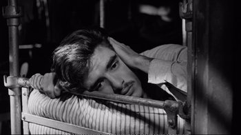 Movie still from “America America” (1963), directed by Elia Kazan – Black and white photograph of a man leaning on a bed; Close Up shot, High angle