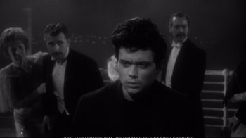 Movie still from “America America” (1963), directed by Elia Kazan – A black and white photo of a man in front of two other men; Close Up shot, Over the shoulder angle