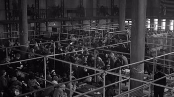 Movie still from “America America” (1963), directed by Elia Kazan – A group of people sitting around in a room; Wide shot, High angle