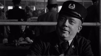 Movie still from “America America” (1963), directed by Elia Kazan – A man in a uniform sitting in front of a crowd; Close Up shot, Over the shoulder angle