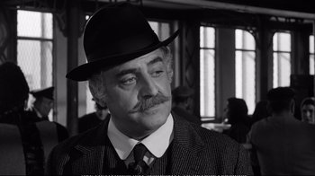 Movie still from “America America” (1963), directed by Elia Kazan – A man with a mustache wearing a suit and a hat; Close Up shot, Over the shoulder angle