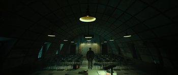 Movie still from “American Dharma” (2018), directed by Errol Morris – A man standing in front of an audience in a building; Extreme Wide shot, Low angle