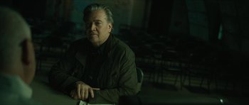 Movie still from “American Dharma” (2018), directed by Errol Morris – A man sitting in front of a bunch of chairs; Medium shot, Low angle