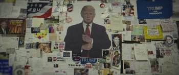 Movie still from “American Dharma” (2018), directed by Errol Morris – A picture of donald trump is on a wall covered in stickers; Extreme Close Up shot, High angle