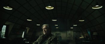 Movie still from “American Dharma” (2018), directed by Errol Morris – A man sitting in front of a ceiling with lights above him; Medium shot, Low angle