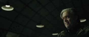 Movie still from “American Dharma” (2018), directed by Errol Morris – A man standing in front of a ceiling with lights in the background; Close Up shot, Low angle