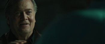 Movie still from “American Dharma” (2018), directed by Errol Morris – An older man is smiling for the camera; Close Up shot, Over the shoulder angle