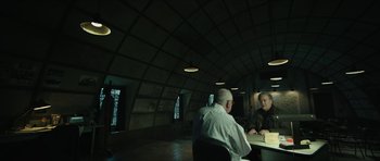 Movie still from “American Dharma” (2018), directed by Errol Morris – Two older men sitting at a table in a room; Wide shot, Low angle
