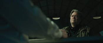 Movie still from “American Dharma” (2018), directed by Errol Morris – A man sitting at a table with a bottle in front of him; Close Up shot, Low angle