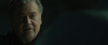 Movie still from “American Dharma” (2018), directed by Errol Morris – An older man with grey hair is looking at the camera; Close Up shot, Over the shoulder angle