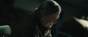 Movie still from “American Dharma” (2018), directed by Errol Morris – An older man with long grey hair looking down at his face; Close Up shot, Low angle