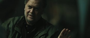 Movie still from “American Dharma” (2018), directed by Errol Morris – An older man with a goatee is looking at the camera; Close Up shot, Over the shoulder angle