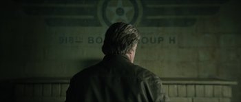Movie still from “American Dharma” (2018), directed by Errol Morris – A man in a green jacket is looking at a wall; Medium shot, Over the shoulder angle