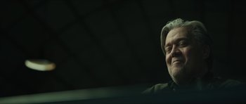 Movie still from “American Dharma” (2018), directed by Errol Morris – An older man with a gray beard and a gray hat; Close Up shot, Low angle